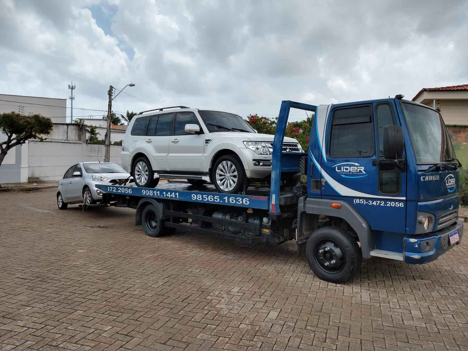 caminhão plataforma com um carro na plataforma e um carro no guincho