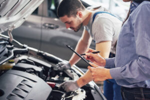 homem mexendo na parte interna do capô do carro