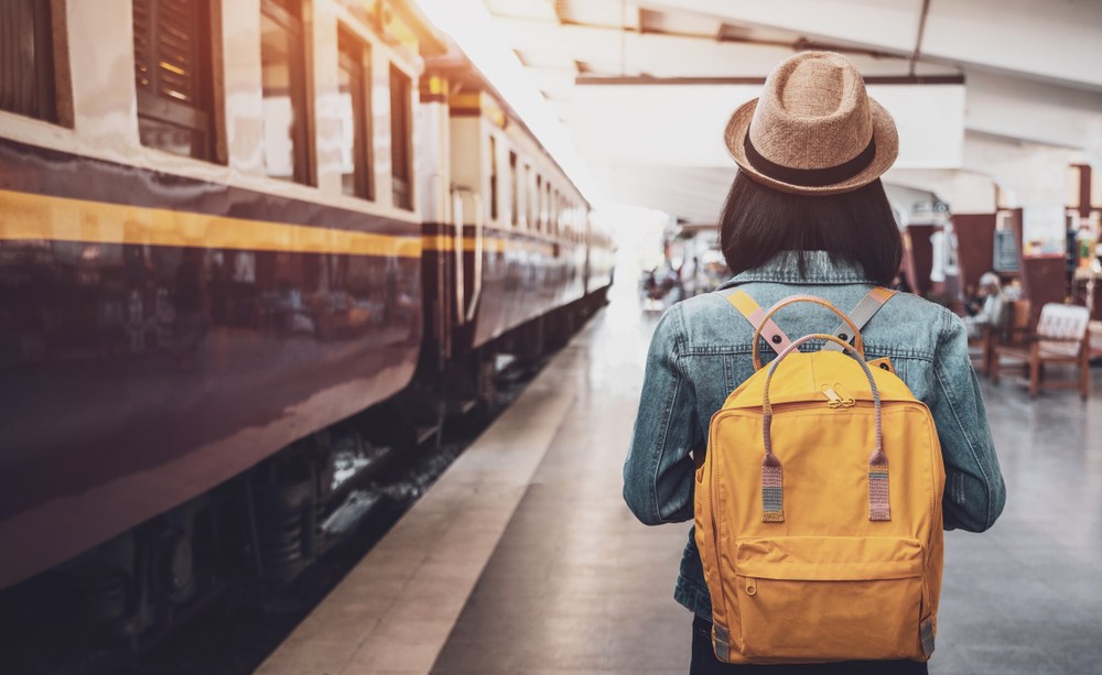 mulher de costas com mochila em meio a uma estação de trem
